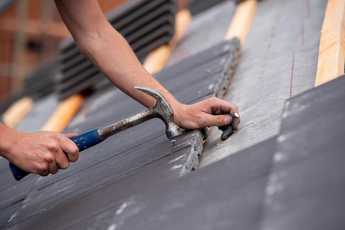 Close-up of skilled builder hands placing roofing tiles