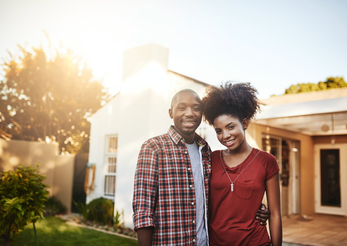 Portrait of a young couple standing outside in front of their new house